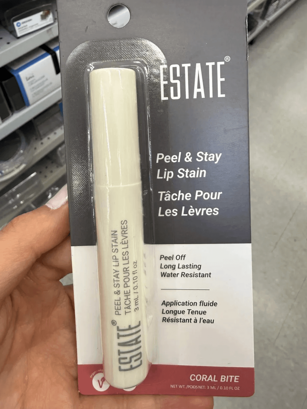 Hand holding Estate Peel & Stay Lip Stain packaging in "Coral Bite".