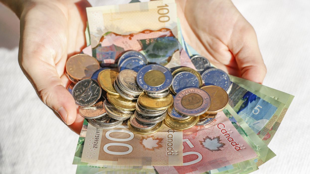 Hands holding a pile of Canadian cash.
