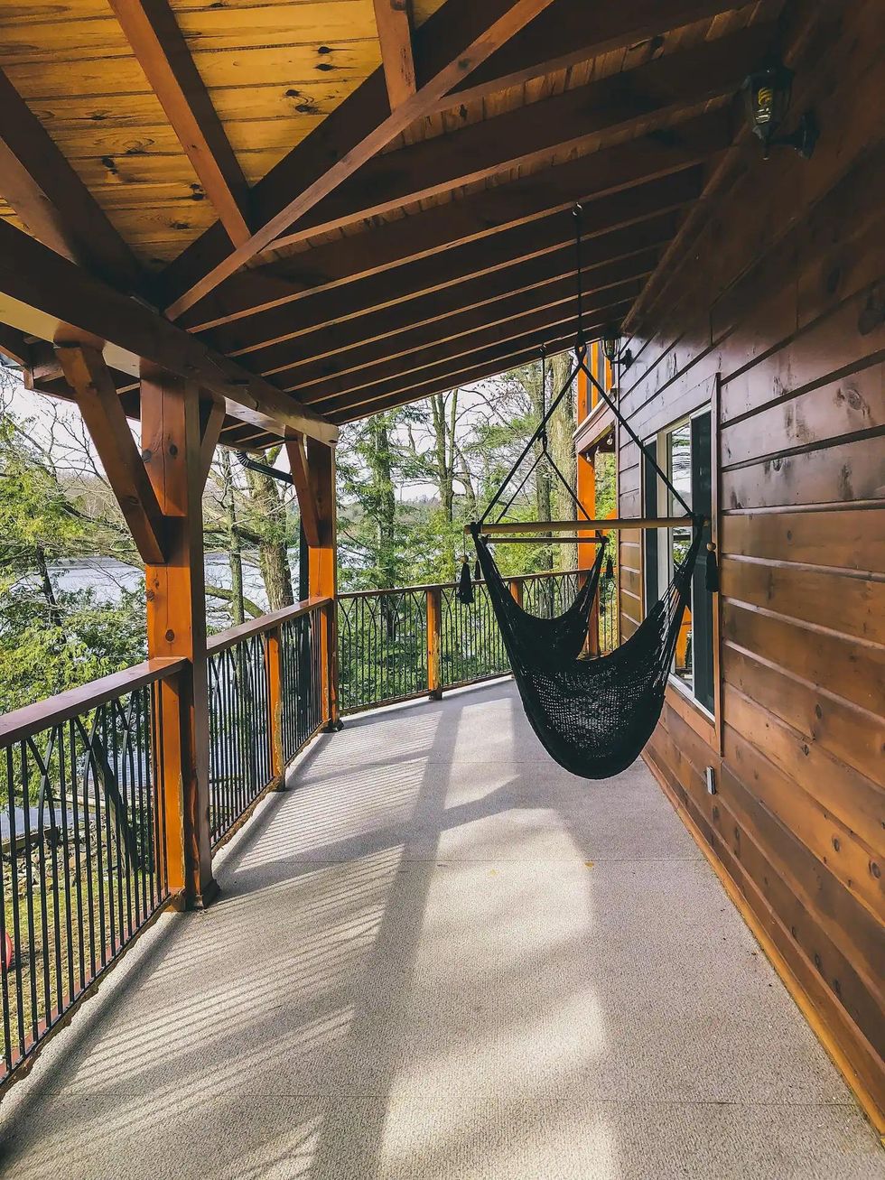 Hanging hammock chairs on an outdoor patio overlooking a lake.