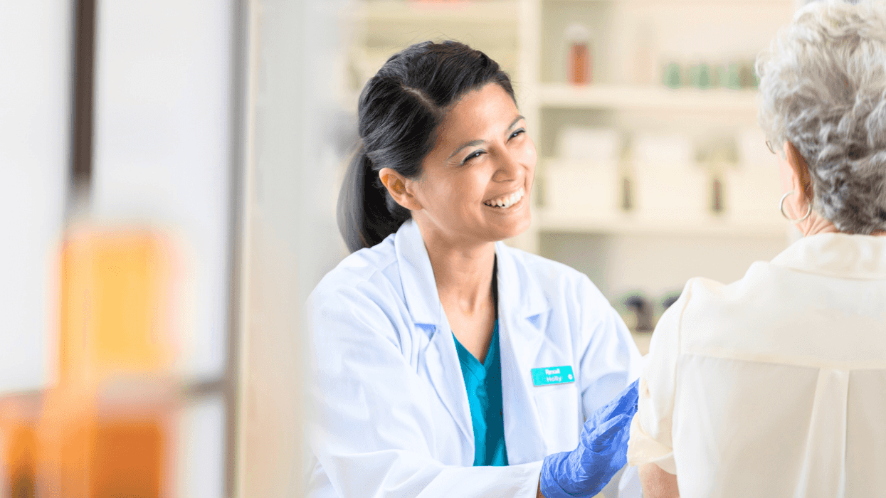 Healthcare worker smiles while administering a vaccine to an elderly woman.