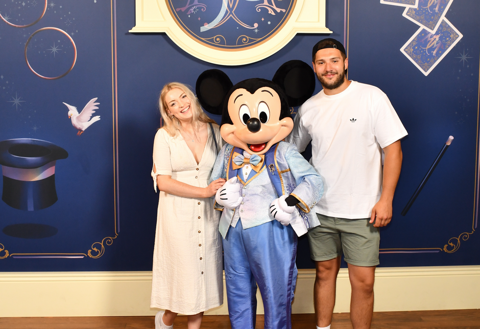 Helena and Amos pose and smile alongside Mickey Mouse.