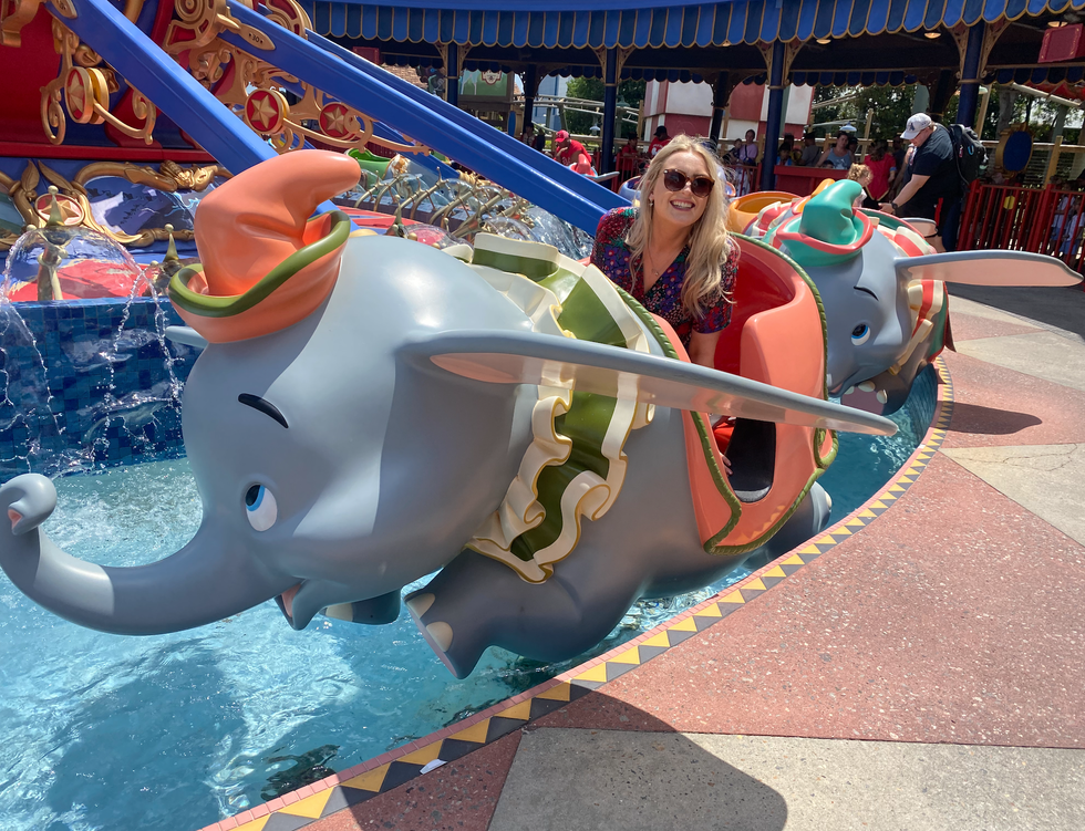 Helena smiles while sitting inside the Dumbo ride at Magic Kingdom.