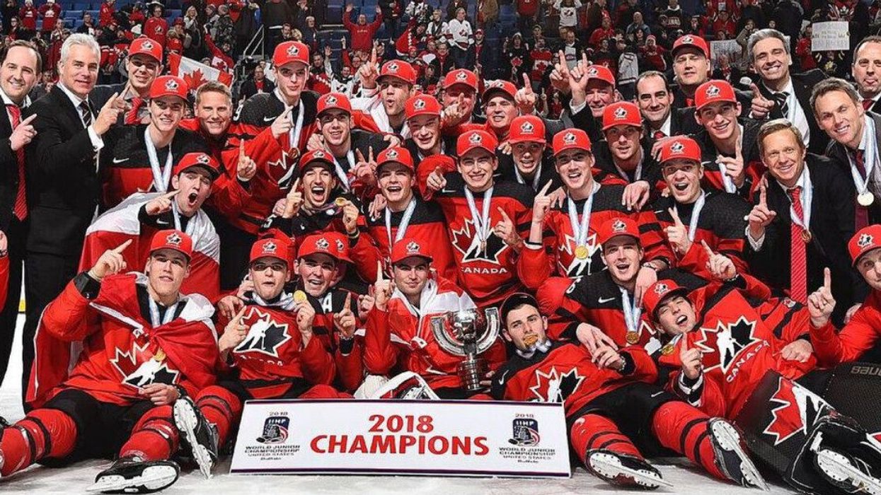 Hockey Canada's World Junior team after winning gold at the 2018 tournament with all the players posing for a picture on the ice with the 2018 Champions banner.
