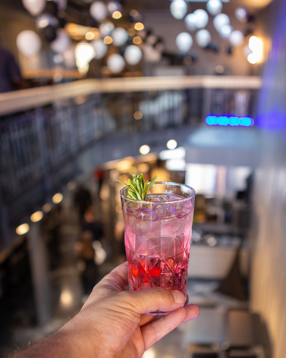 Holding cocktail in J'TM Resto Bar from indoor balcony view.