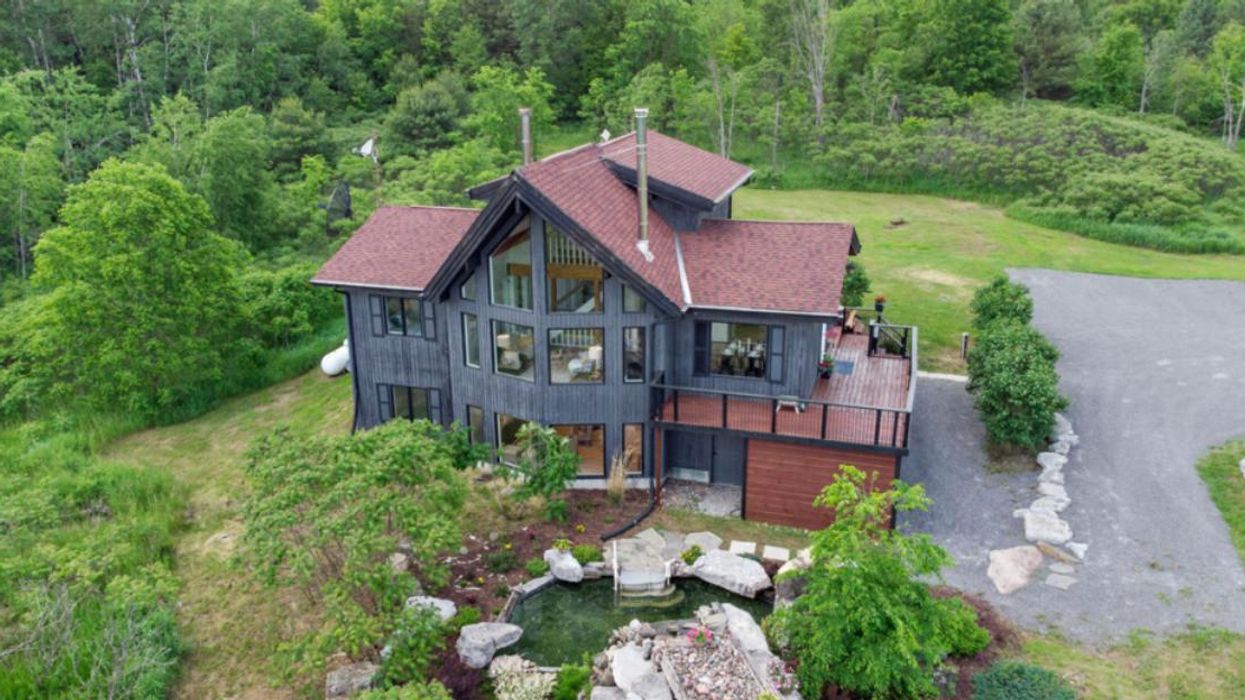 Home for sale with large windows and a pond.