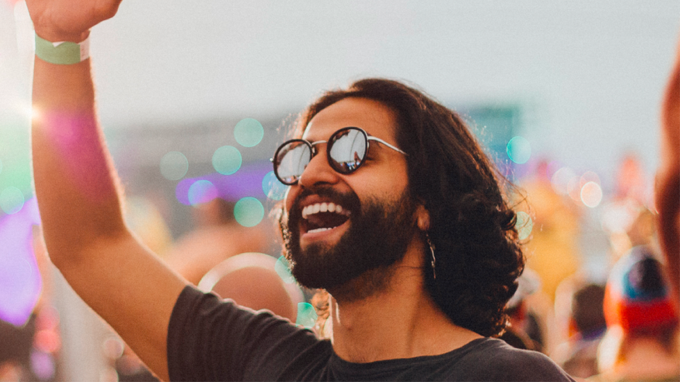 Homme souriant avec des lunettes de soleil pendant un festival en plein air.