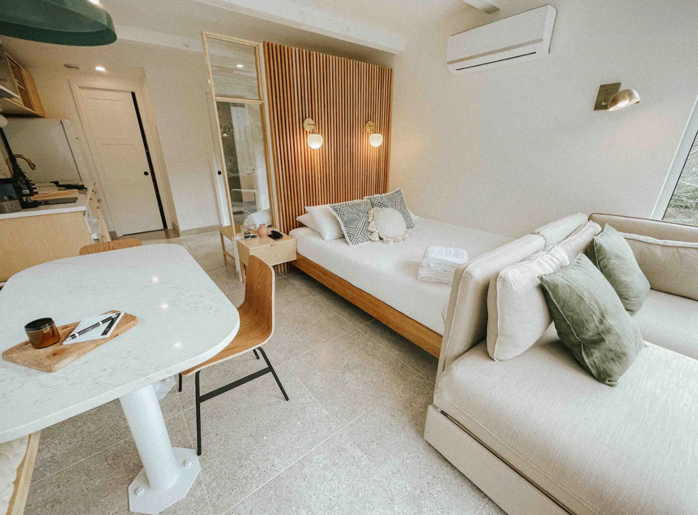 Int\u00e9rieur au d\u00e9cor scandinave d'un airbnb, une cuisinette, une table avec deux chaises, un lit et un divan