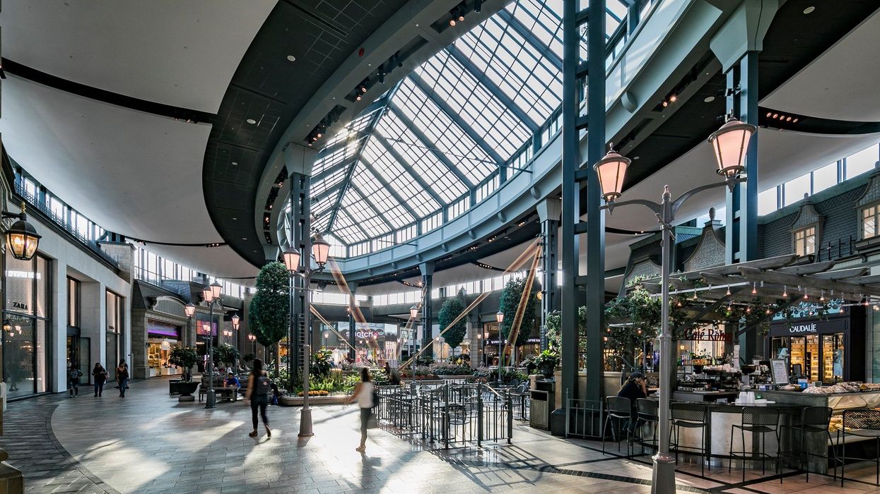 Intérieur d'un centre d'achat avec plusieurs boutiques et plantes.