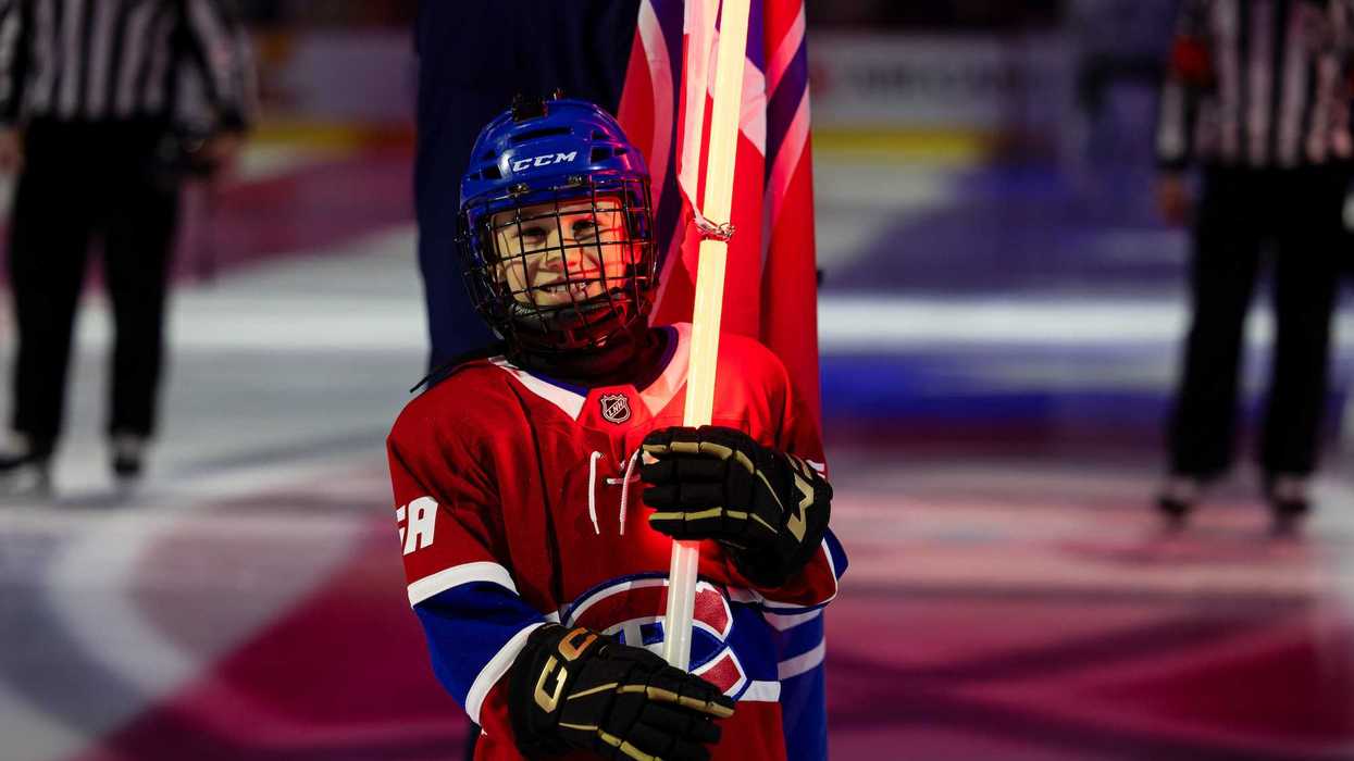 Jeune fan des Canadiens tenant un bâton de hockey lumineux.