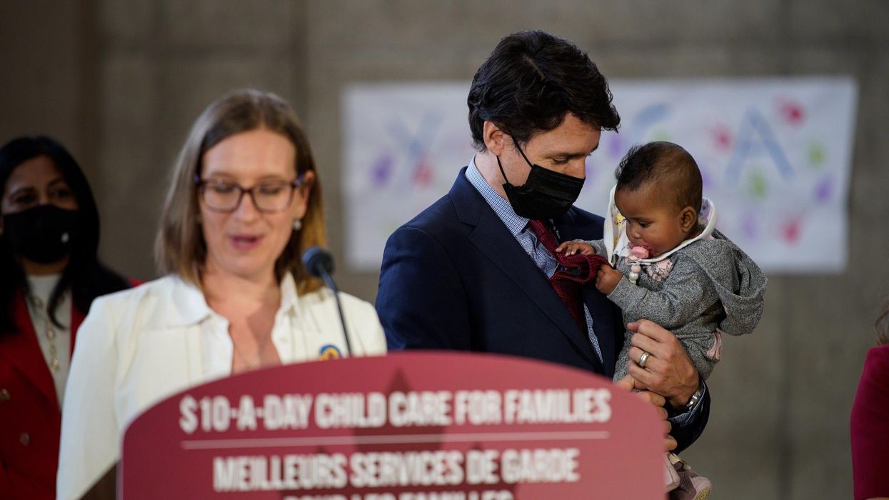 Justin Trudeau holding a baby at a press conference.
