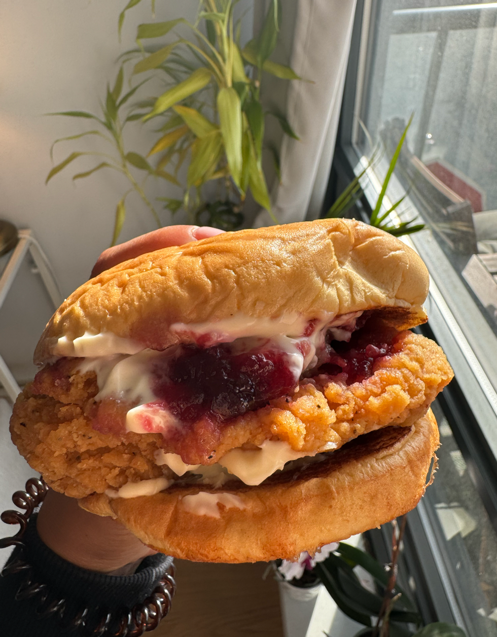 KFC's new Festive Chicken Sandwich with fried chicken, cranberry sauce, stuffing between two buns.