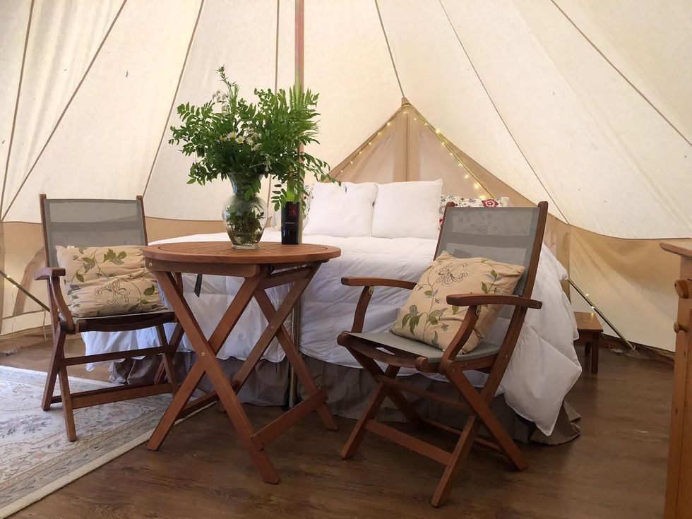 King sized bed in luxury tent Airbnb with wooden table for two, in Lanark Ontario.