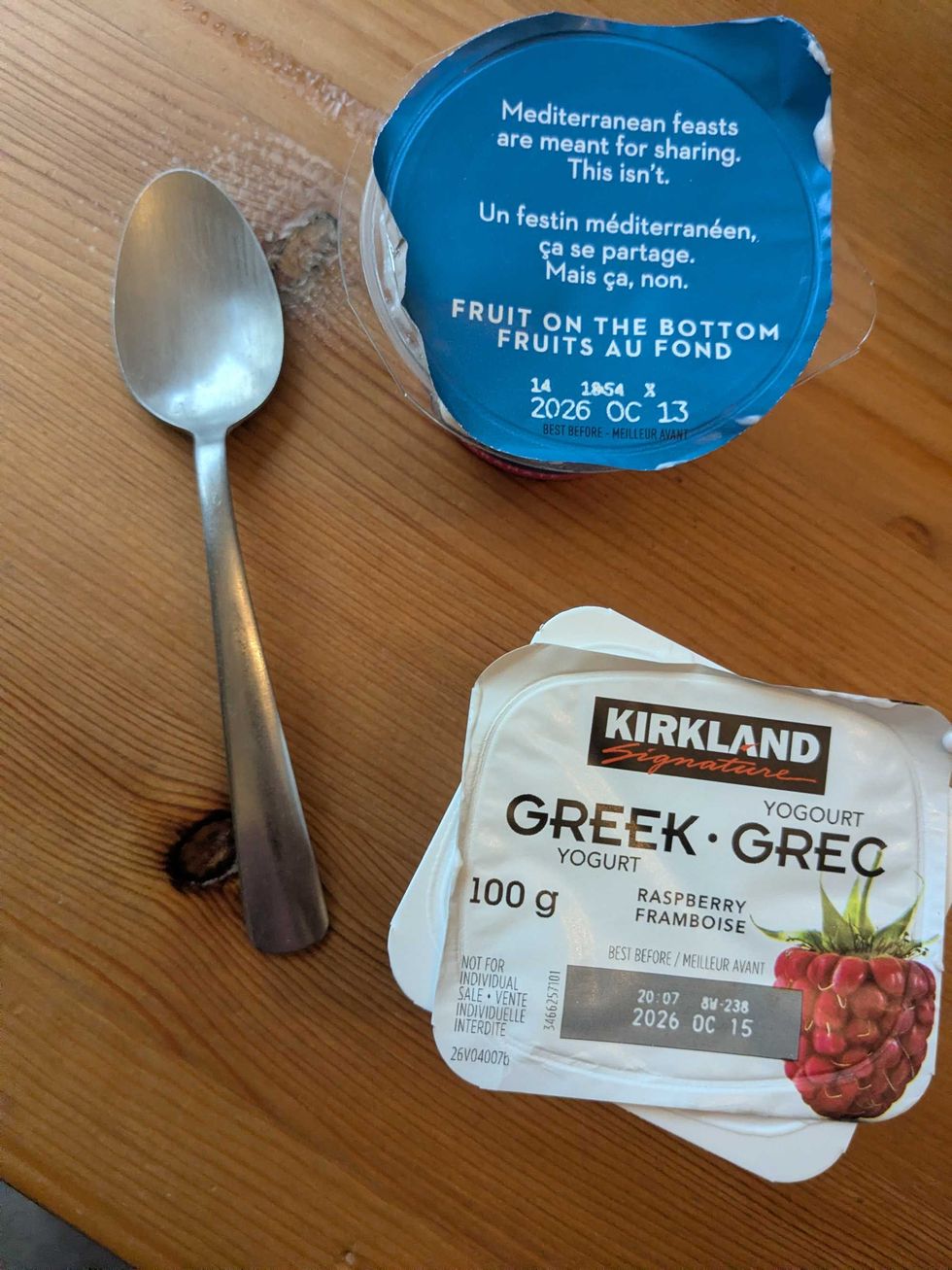 Kirkland and Oikos Greek yogurt containers with a spoon on a table
