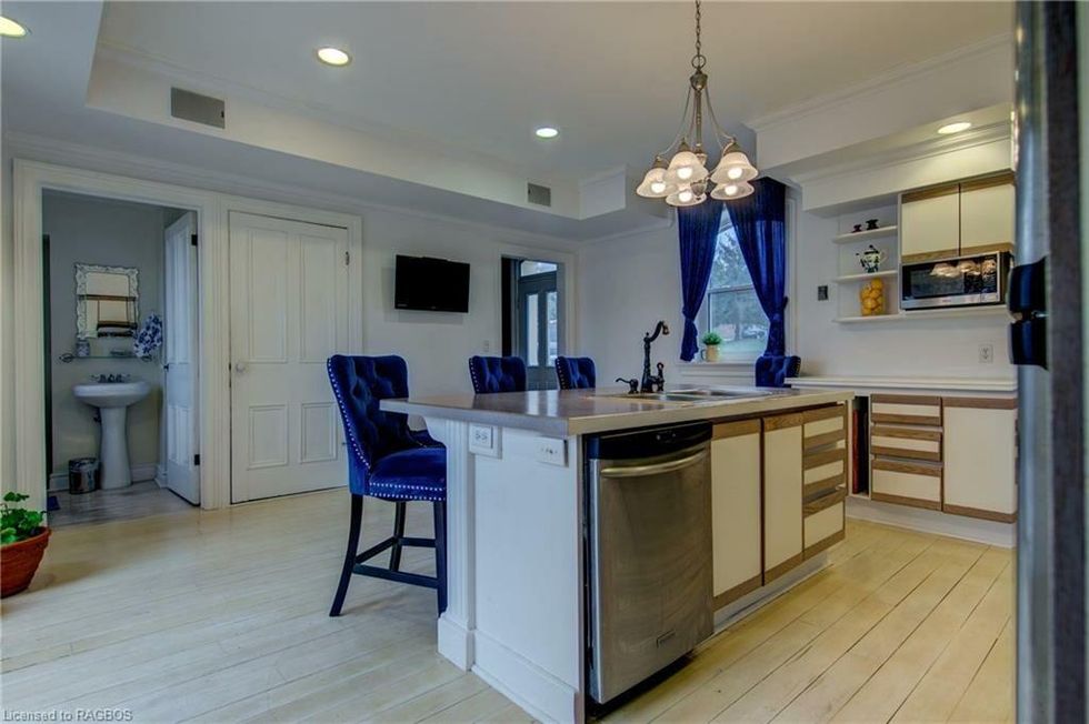 Kitchen with an island and blue chairs.