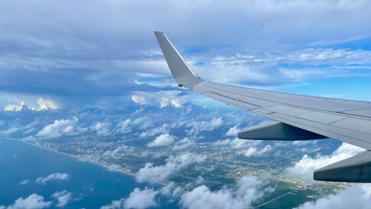 L'aileron d'un avion dans les airs, surplombant les nuages, la mer et une ville américaine.