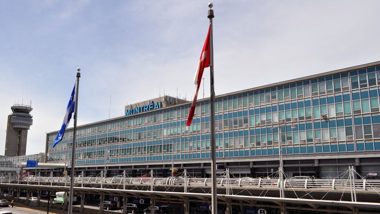 La devanture de l'Aéroport International Montréal-Trudeau avec deux drapeaux et le mot Montréal écrit en bleu.