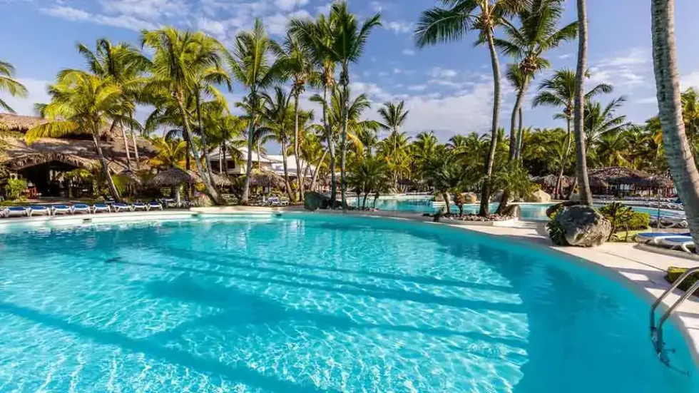 La piscine du Playabachata Hotel en R\u00e9publique dominicaine entour\u00e9e de palmiers.