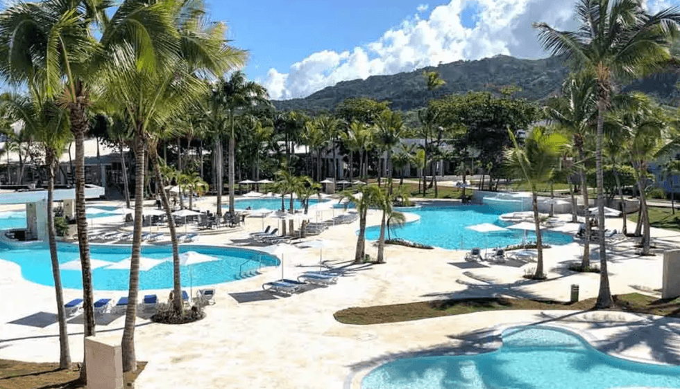 La piscine du Senator Puerto Plata Hotel entour\u00e9e de palmiers.