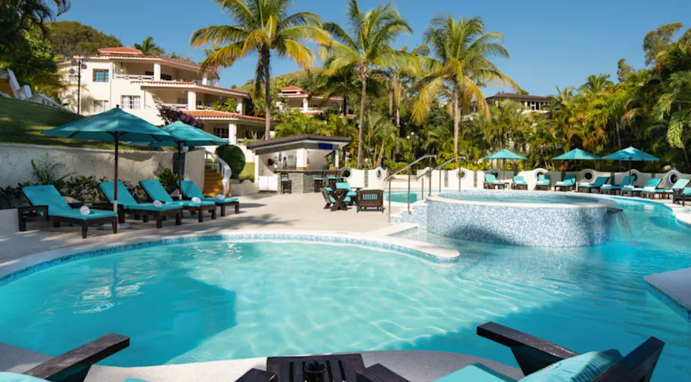 La piscine entour\u00e9e de chaises longues et de palmiers de l'h\u00f4tel Lifestyle Residence Suites.