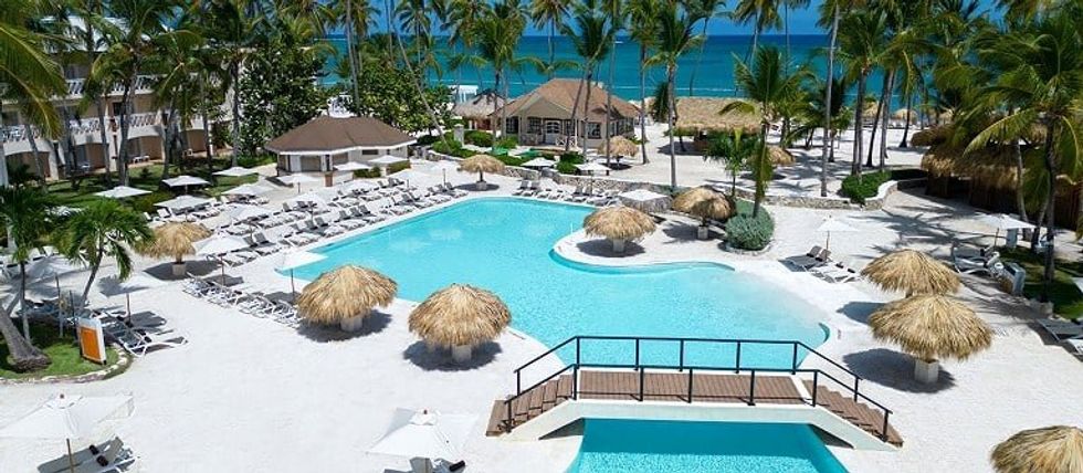 La piscine entour\u00e9e de palmiers, de chaises longues et de palapas du resort Sunscape Coco Punta Cana.