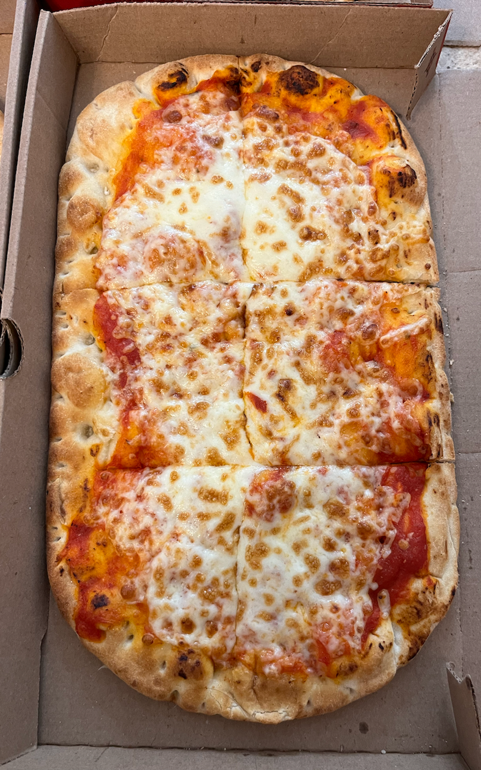La pizza sur pain plat \u00e0 saveur Simplement fromage du Tim Hortons dans sa bo\u00eete.