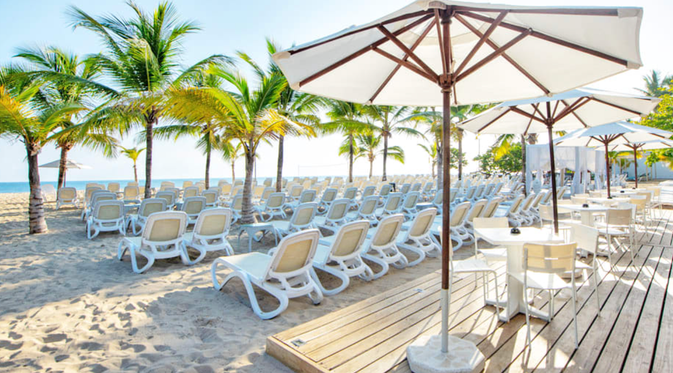 La plage de sable blanc de l'h\u00f4tel Viva Heavens by Wyndham en R\u00e9publique dominicaine, avec des chaises longues et des palmiers.