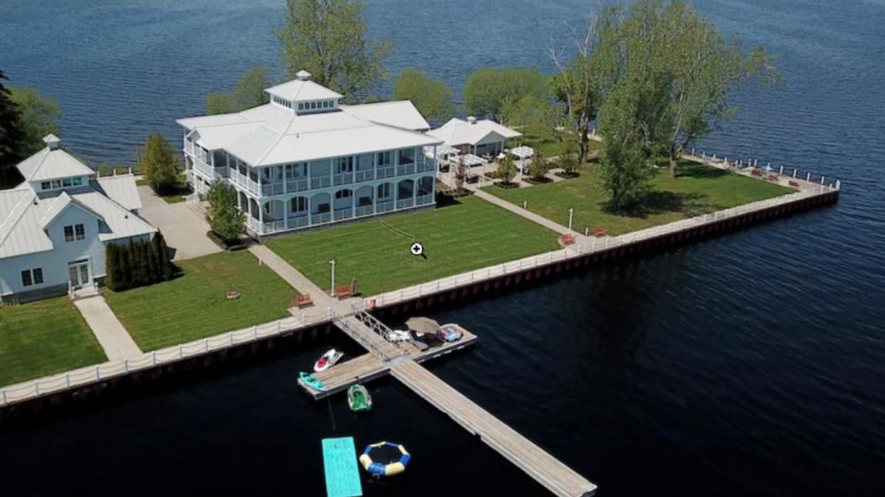 Large house with wrap-around porch surrounded by water.