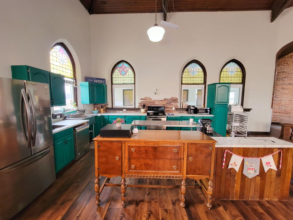 Large kitchen with island and double fridge with light from stained glass windows.