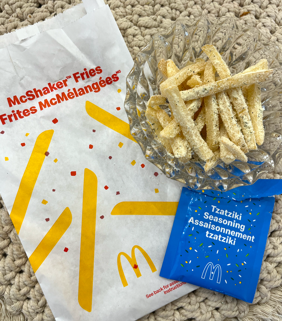 Le sac pour m\u00e9langer les frites, le sachet d'assaisonnement tzatziki, ainsi que les frites assaisonn\u00e9es.