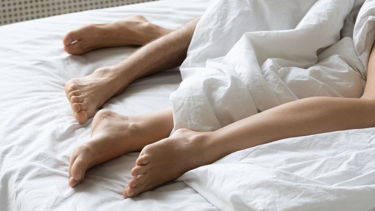 Legs of two people in bed together.