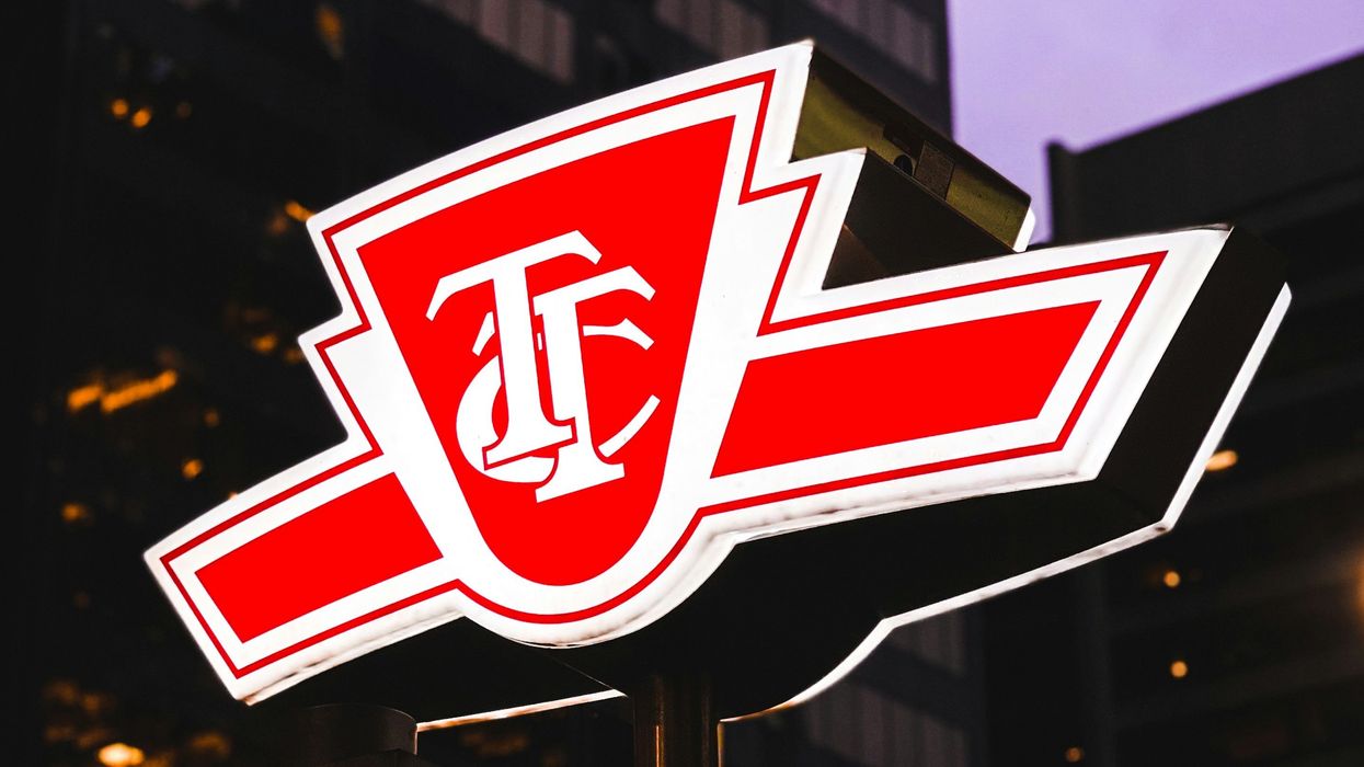lit up red and white ttc sign in toronto at night