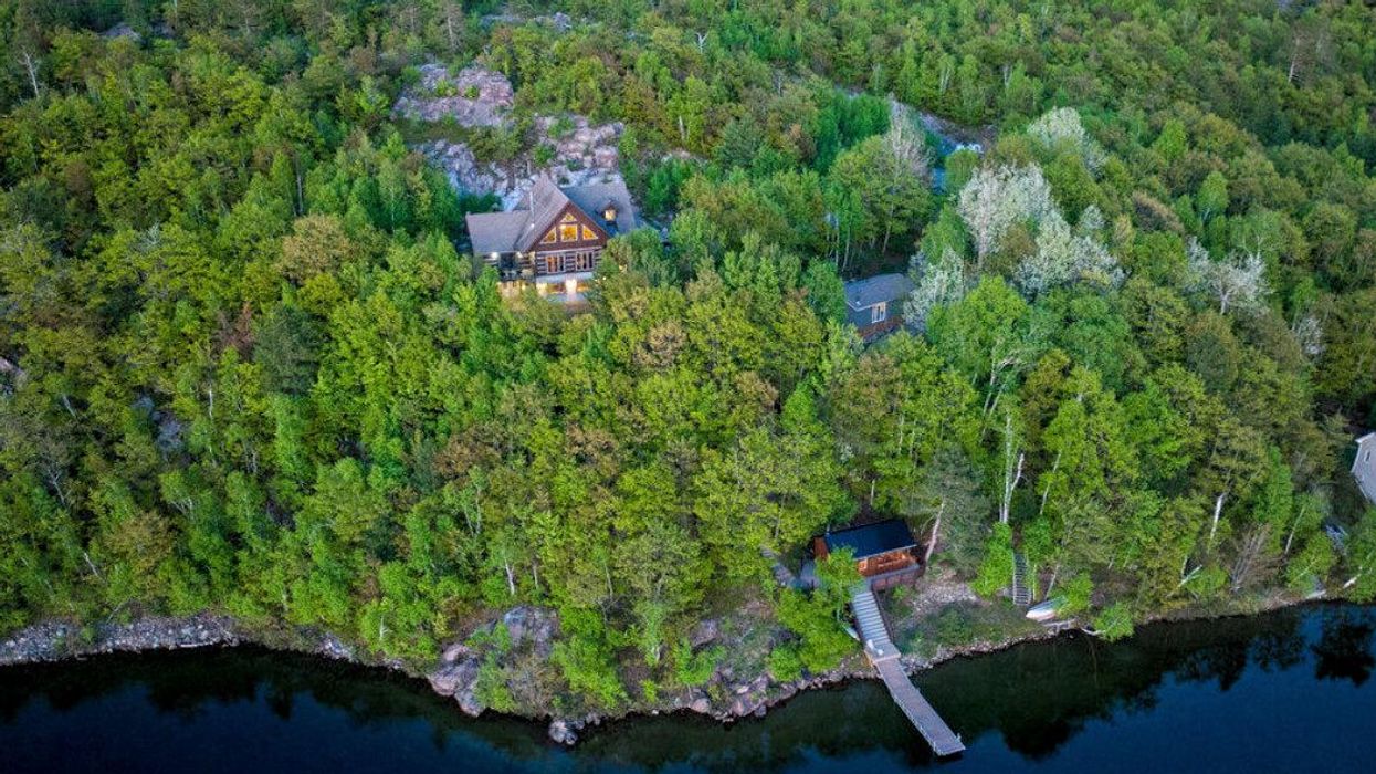 Log house on a lake surrounded by trees.
