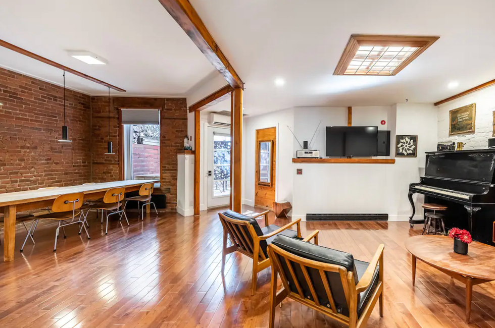 Logement vintage avec un mur de briques, des chaises ainsi qu'une table.