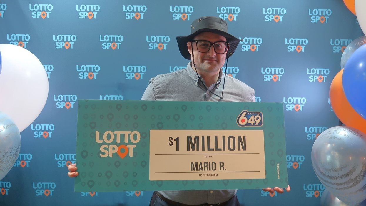 lotto 6/49 winner mario raimondi holding a $1 million cheque