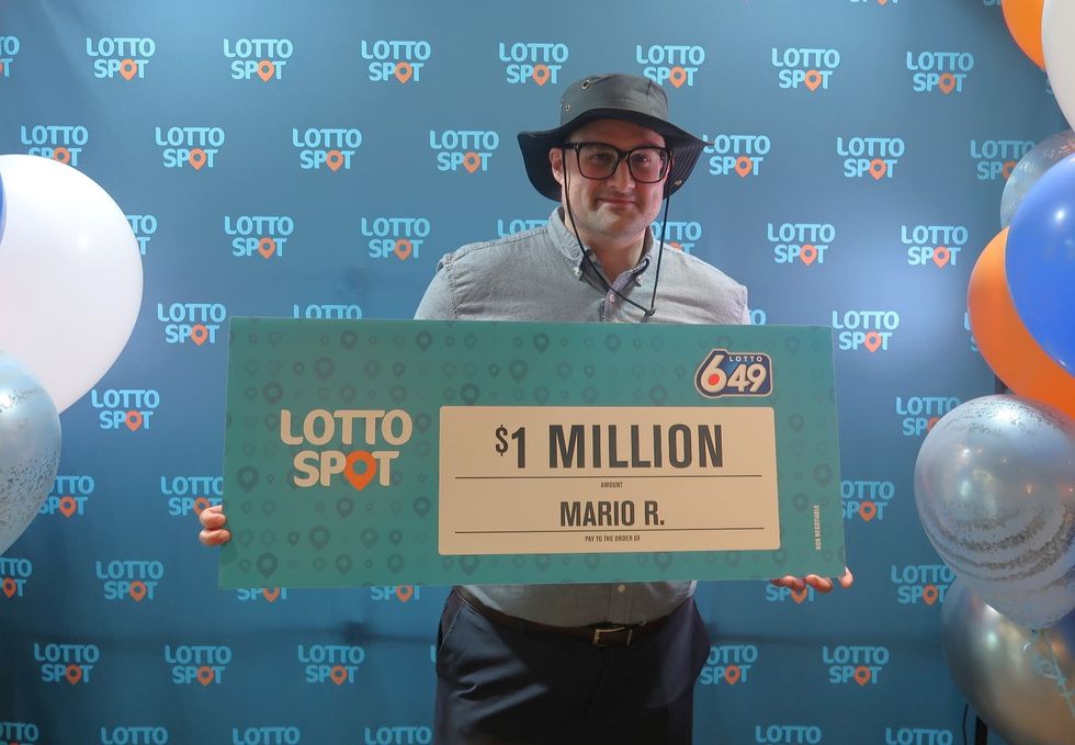 lotto 6/49 winner mario raimondi standing with a $1 million cheque