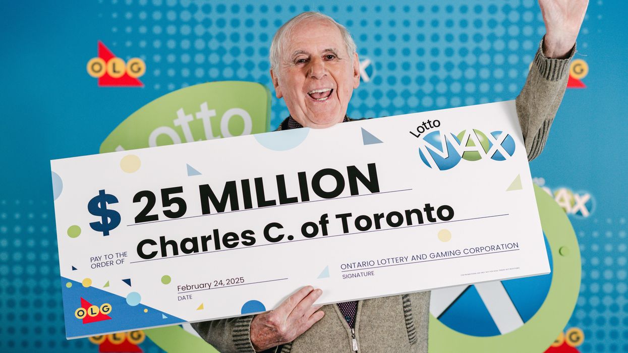 lotto max winner charles coffey holding a $25 million cheque