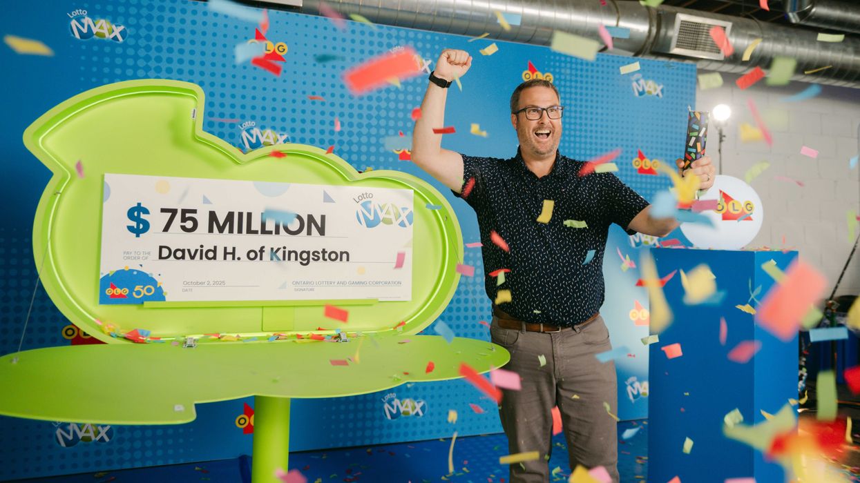 lotto max winner david hatt standing next to a $75 million cheque