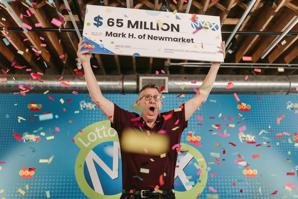 lotto max winner mark hanley holding a $65 million cheque as confetti falls