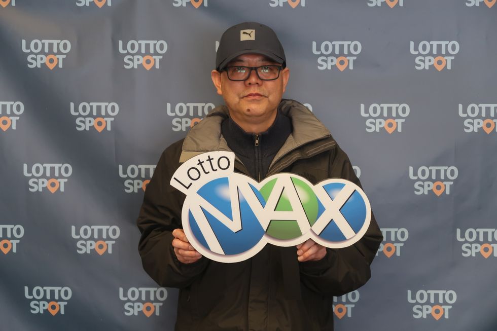 lotto max winner ming zhu with a lotto max sign