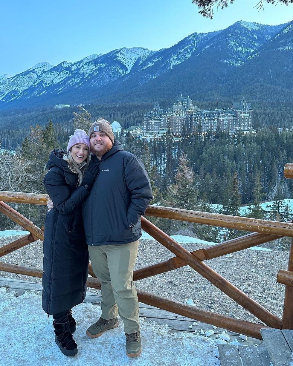 Luke Combs and his wife Nicole standing in front of a stunning view of Banff.