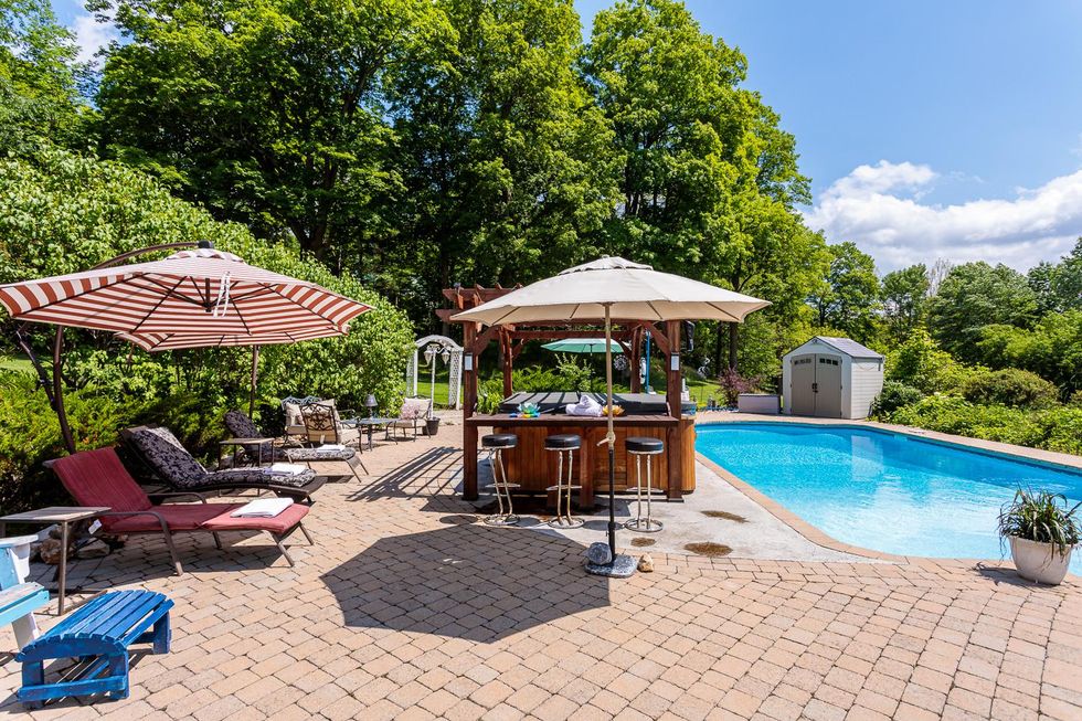 Luxury spa backyard with inground pool and hot tub surrounded by forest.