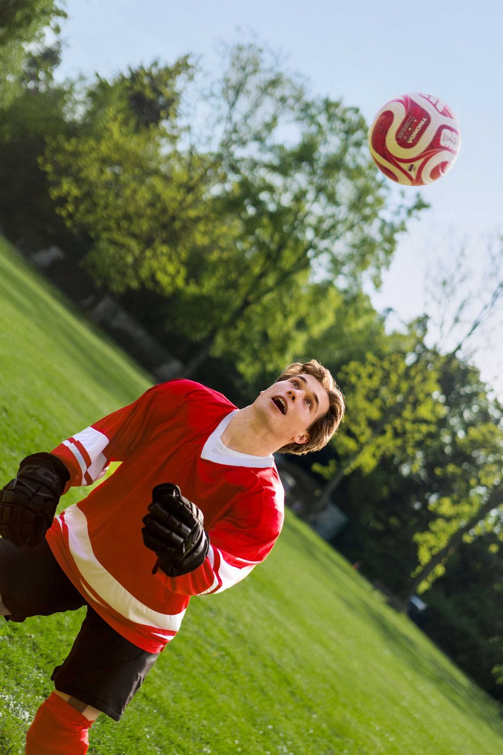 Macklin Celebrini juggles a soccer ball while wearing hockey gloves.