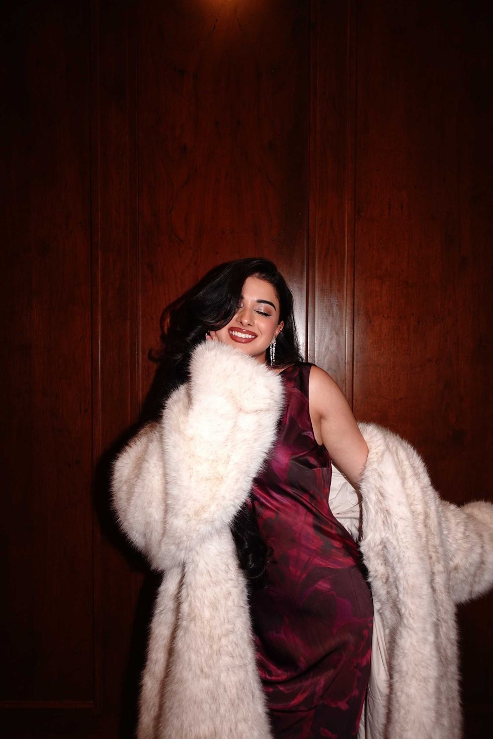 Mahnoor Naeem in a burgundy dress and fur coat.