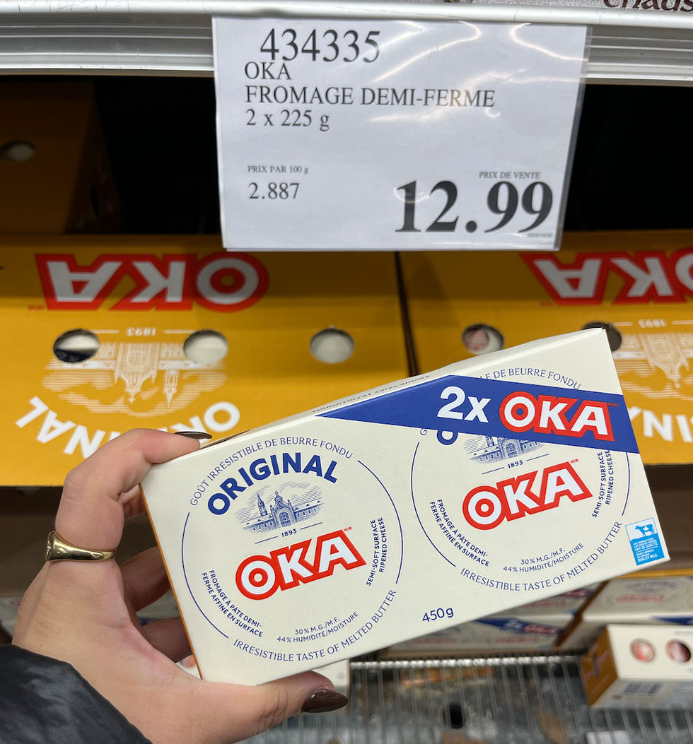 Main qui tient un emballage de deux fromages demi-fermes OKA.