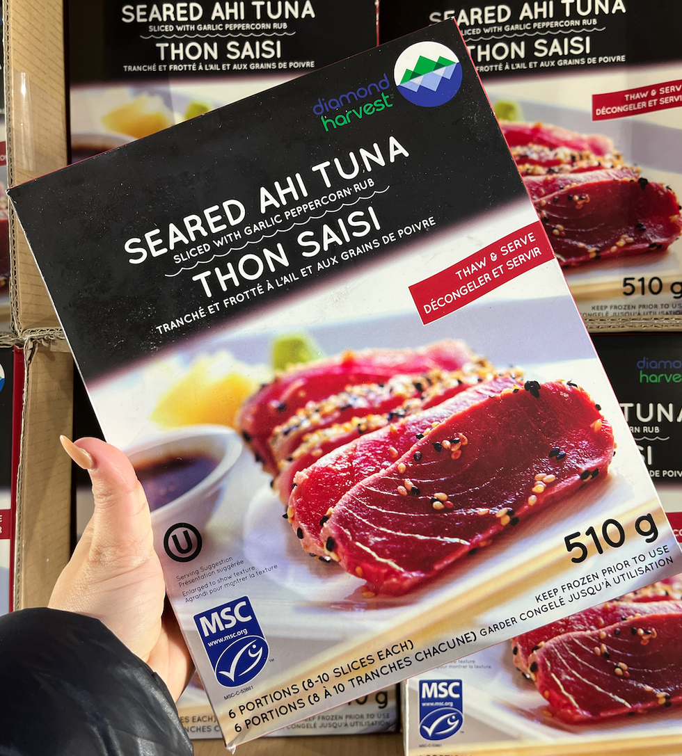 Main qui tient une bo\u00eete de 6 portions de tataki de thon congel\u00e9.