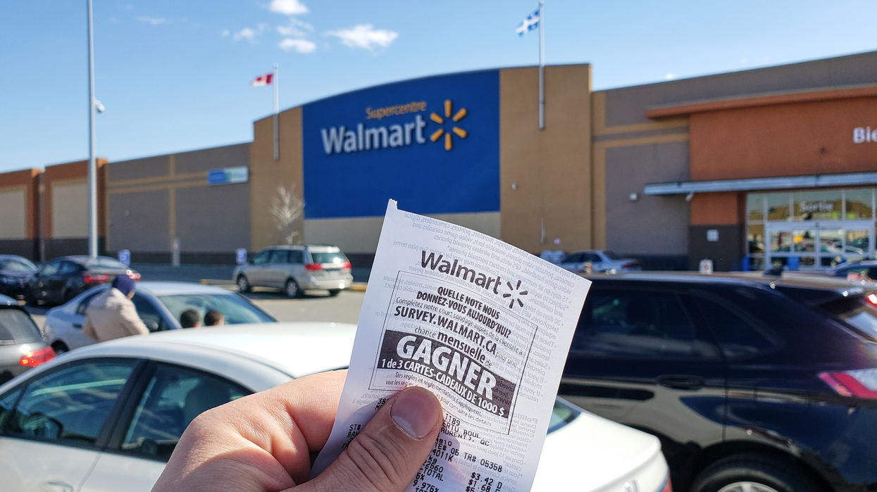Main qui tient une facture du Walmart devant la devanture du magasin.