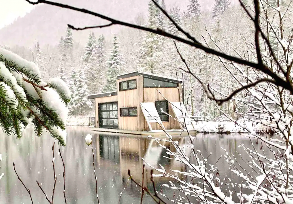 maison flottante sur l'eau dans la for\u00eat lors d'une tomb\u00e9e de neige.