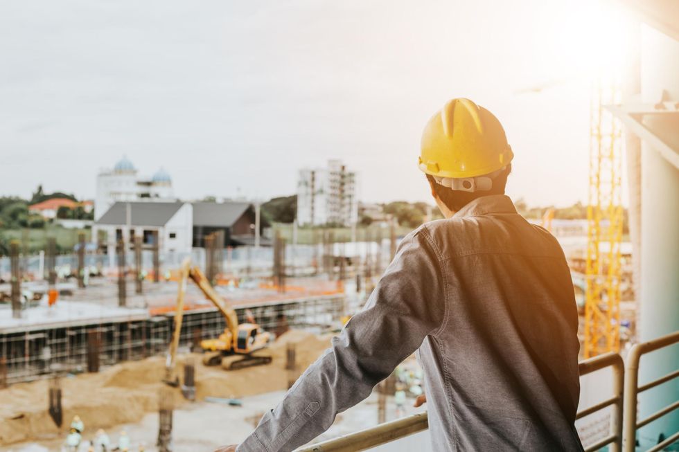 Man in a hard hat overlooking a construction site.