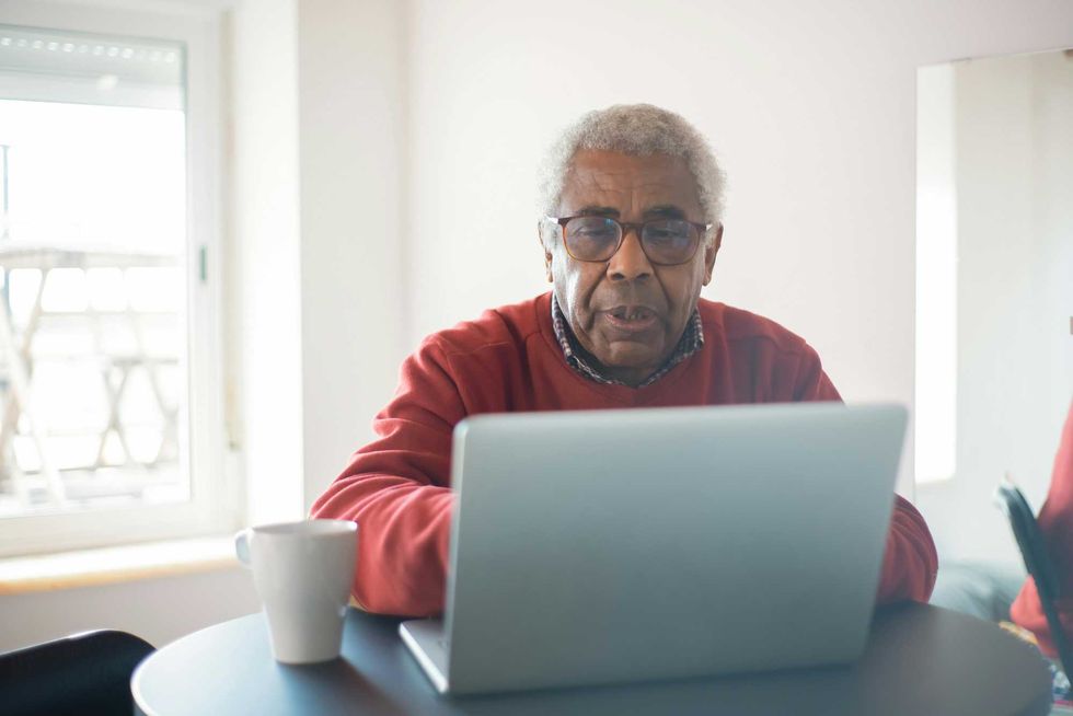 Man in red sweater using laptop.