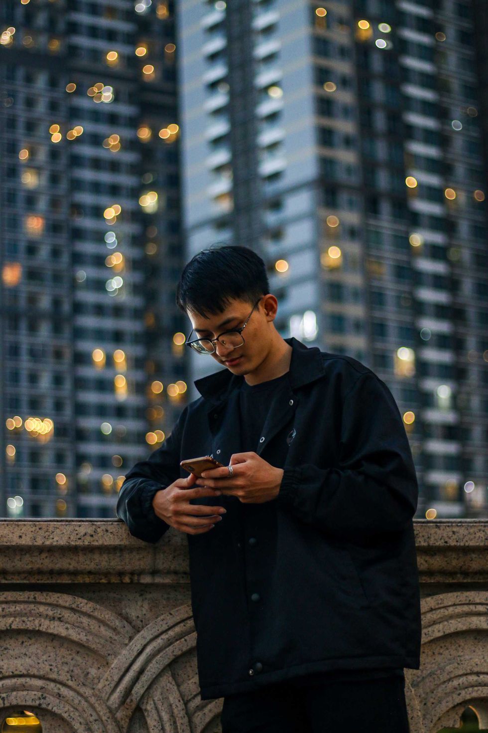 Man using a smartphone in an urban setting at night.